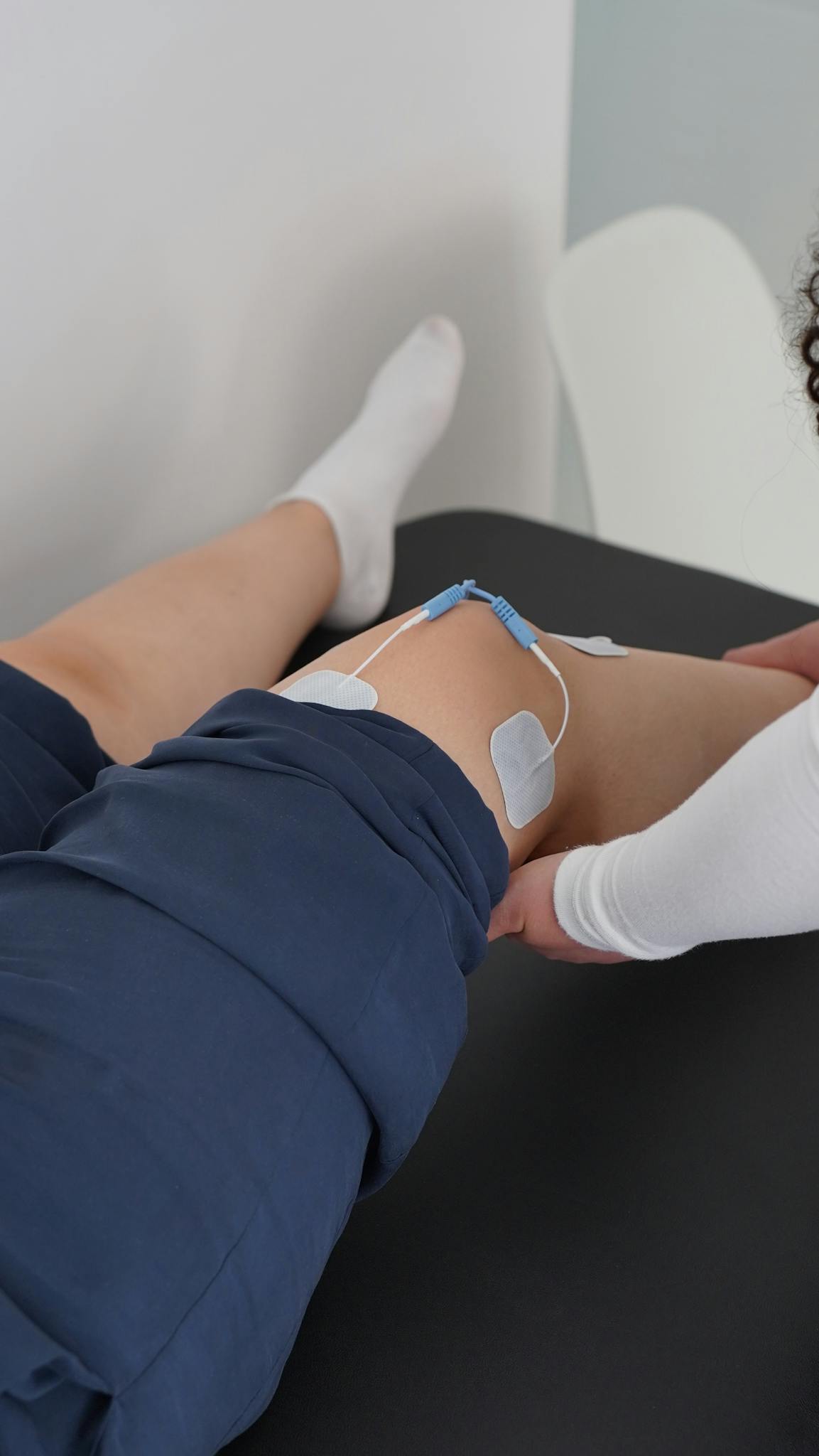 Electrotherapy applied during a knee physiotherapy session for muscle recovery.